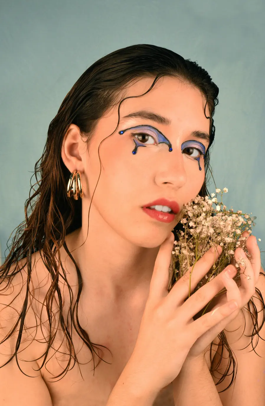 Editorial makeup photography, with flowers in the hand, capturing the delicacy of the makeup and the visual connection between the model and natural elements.